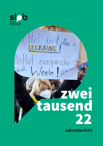 Cover des Jahresberichts der SLpB mit dem Titel "zweitausend22. Jahresbericht." Auf dem Cover ist eine Frau zu sehen, die ein Schild in blau-gelb mit der Aufschrift "Rettet das Leben in Ukraine! Rettet europäische Freiheit Werte Selbstbestimmung! Bei Klick Download des Jahresberichts als PDF.
