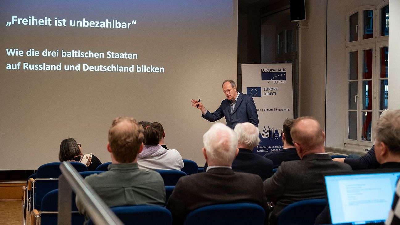 Mann hält Vortrag vor Publikum in einem Seminarraum mit Präsentation zum Thema Freiheit und baltische Staaten