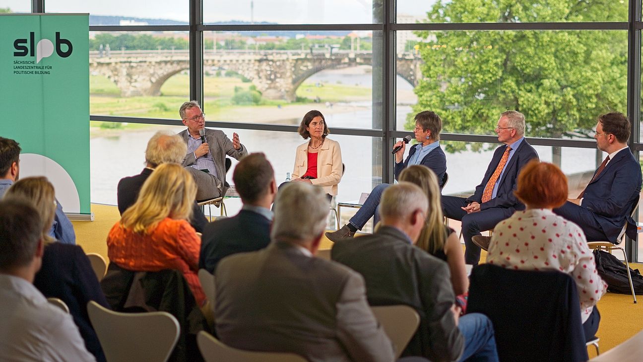 odiumsdiskussion im Bürgerfoyer des Sächsischen Landtags am 5. Juni mit fünf Personen, darunter Prof. Dr. Johannes Eichenhofer und Prof. Dr. Birgit G, moderiert von Dr. Roland Löffler, vor Publikum mit Blick auf eine Brücke und grüne Landschaft