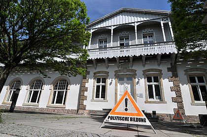 Vor der SLpB steht ein Baustellen-Schild mit der Aufschrfit "! Politische Bildung". Bei Klick vergrößert sich das Bild.
