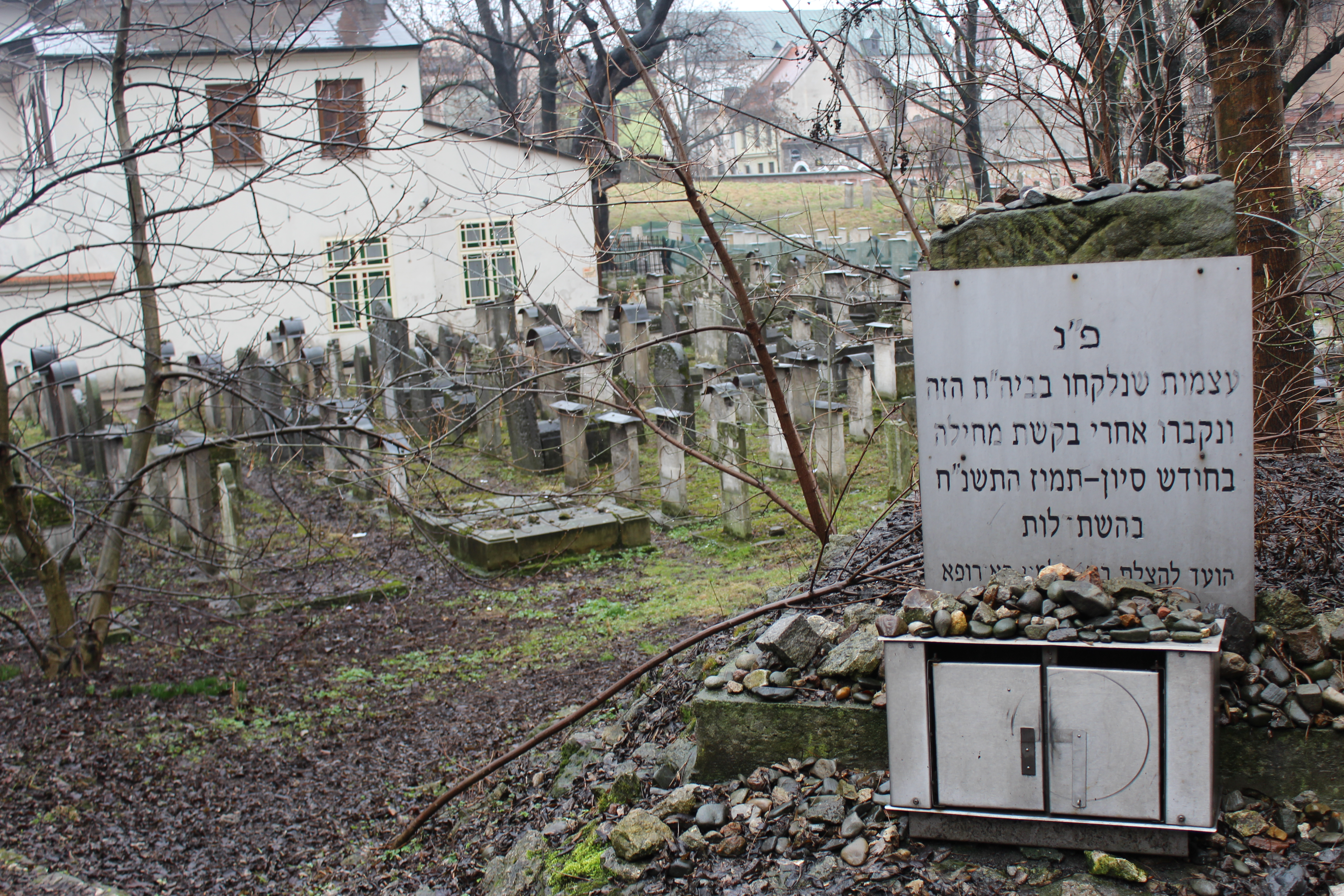 Zu sehen ist ein Friedhof, davor ein Schild mit hebräischer Sprache.