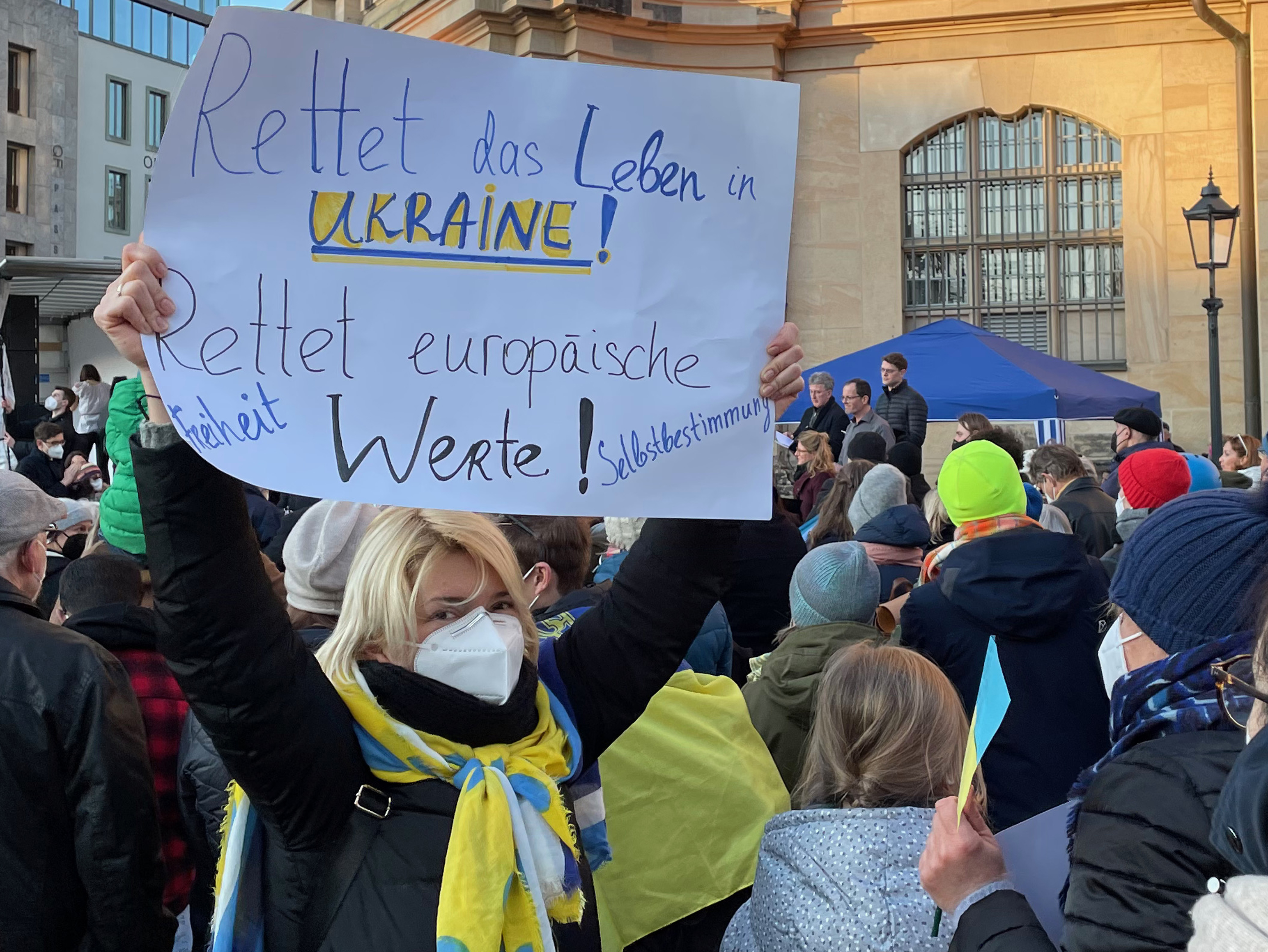 Foto einer Demonstration für die Ukraine in Dresden. Eine Teilnehmerin hält ein Schild mit folgender Aufschrift in die Höhe: "Rettet das Leben in [sic] Ukraine! Rettet europäische Werte! Freiheit, Selbstbestimmung."