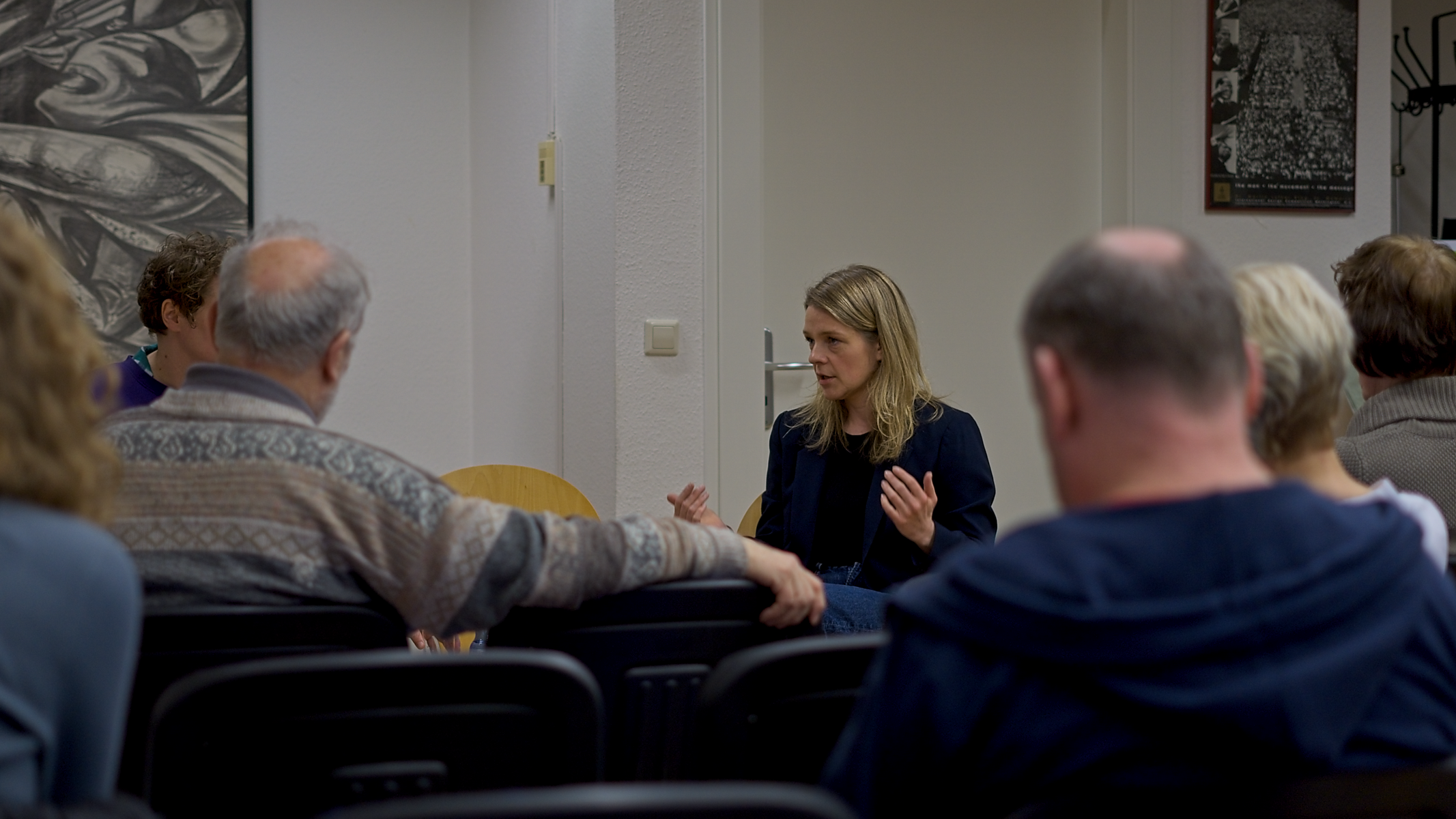 Teresa Tammer gestikuliert während des Gespräches in der Mitte des Bildes. Im Vordergrund sind unscharf weitere Gäste zu erkennen.