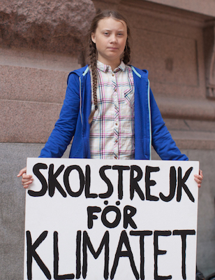 Die Klimaaktivistin Greta Thunberg mit einem Schild in der Hand mit der Aufschrift "Skolstrek För Klimatet" ("Schulstreik für das Klima").